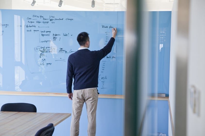 Businessman writing notes on glass board-1